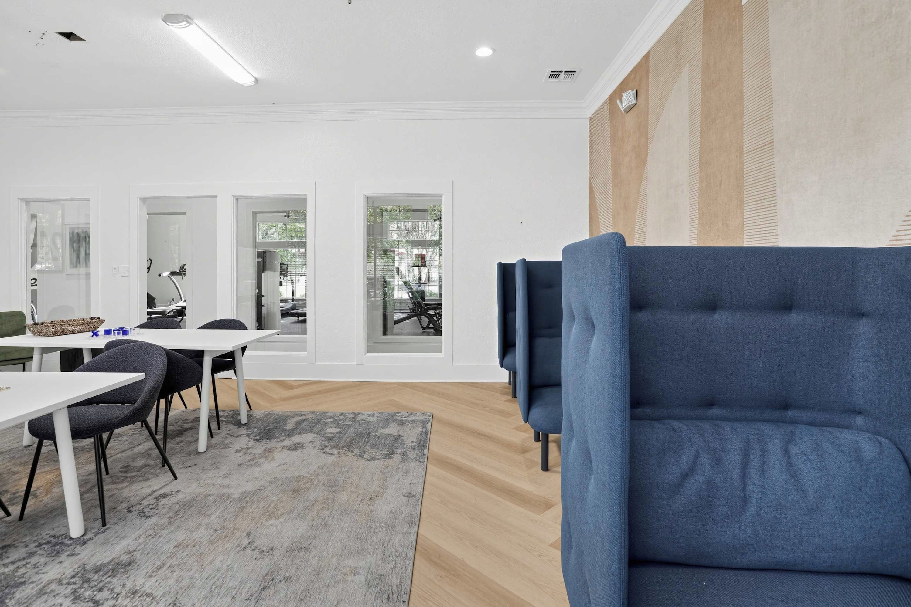 Un interior moderno con comedor, un sofá azul y ventanas amplias.