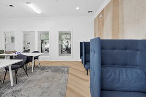Un interior moderno con comedor, un sofá azul y ventanas amplias.