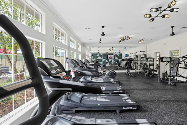 Un gimnasio con cintas de correr, máquinas de pesas y una pantalla de televisión.