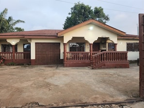 A two-story building with a red roof, a balcony with a wooden railing, and a gated entrance.