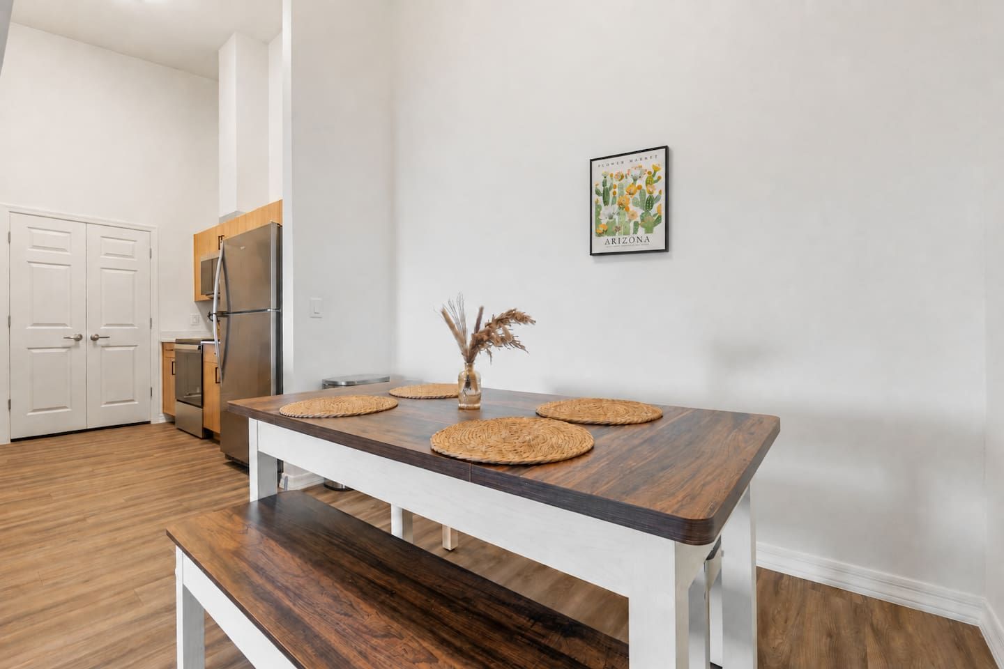 Cozinha moderna com mesa de madeira, armários brancos e geladeira.