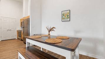 Cozinha moderna com mesa de madeira, armários brancos e geladeira.