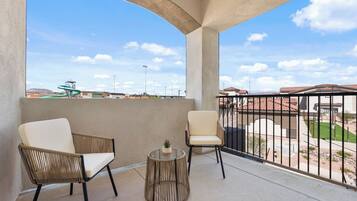 Un balcon avec deux chaises, une petite table ronde et une vue sur un quartier résidentiel.