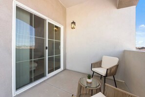 Quiet balcony nook off the living room with sliding glass doors and a cozy woven chair. A perfect little spot for fresh air, morning coffee, or a moment to relax outdoors. - Mesa Getaway | 3 Queen Beds | Near Dining (Mesa)