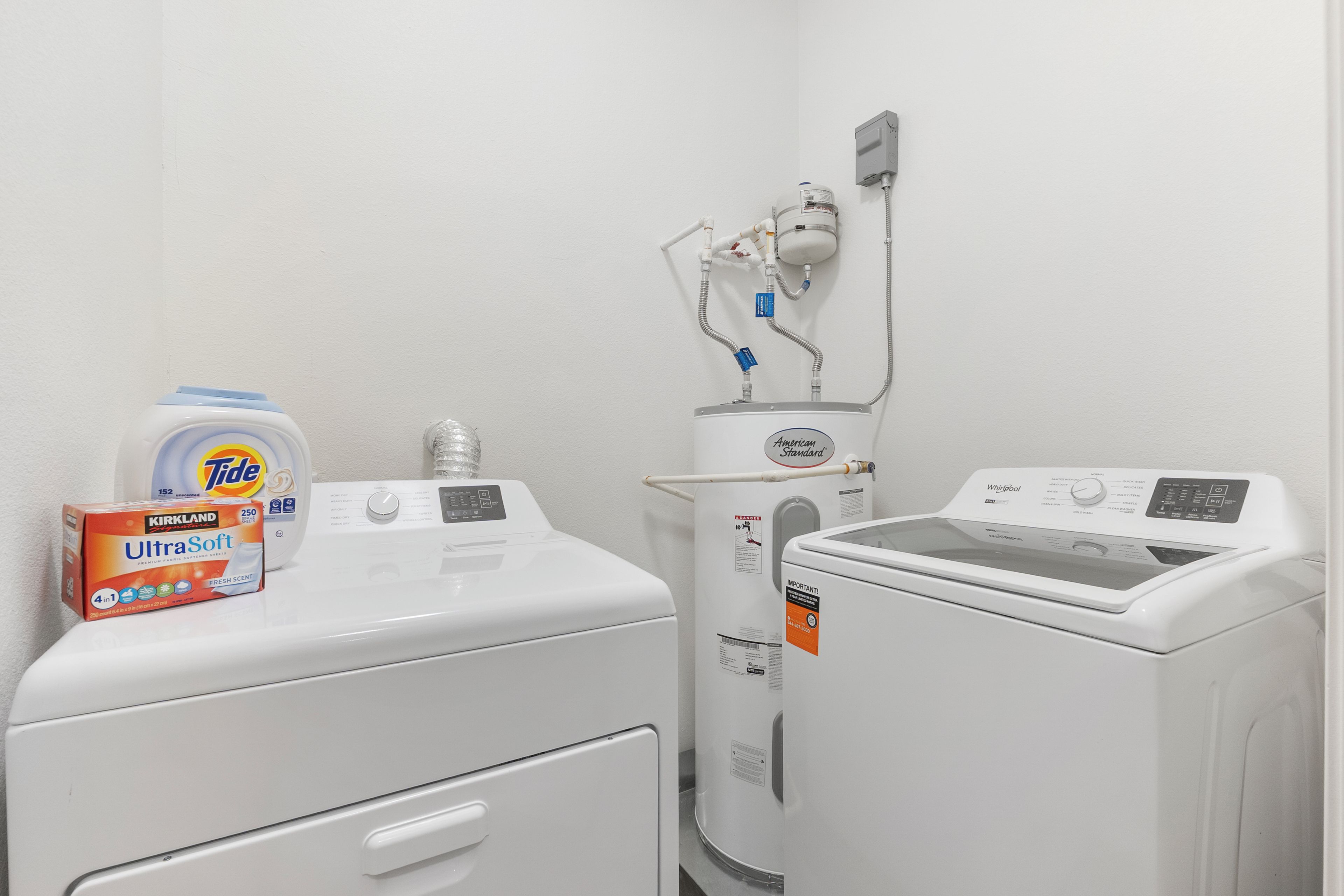 A laundry area with a front-loading washer, a stacked dryer, and a water heater.