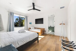 A modern bedroom with a bed, a ceiling fan, a TV, and a view of the outdoors. - East Austin Skyline & Pool House ~Backyard BBQ~ (Austin)