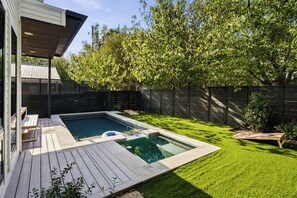 A backyard with a swimming pool, wooden deck, and a grassy lawn. - East Austin Skyline & Pool House ~Backyard BBQ~ (Austin)