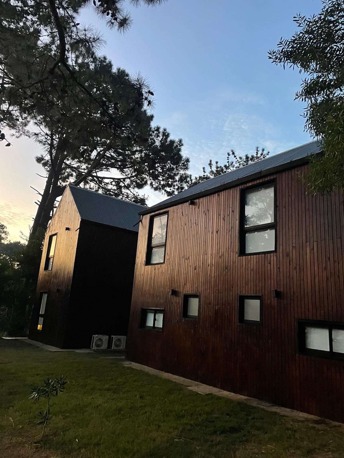 Un edificio moderno con fachada de madera, varias ventanas y techo inclinado.