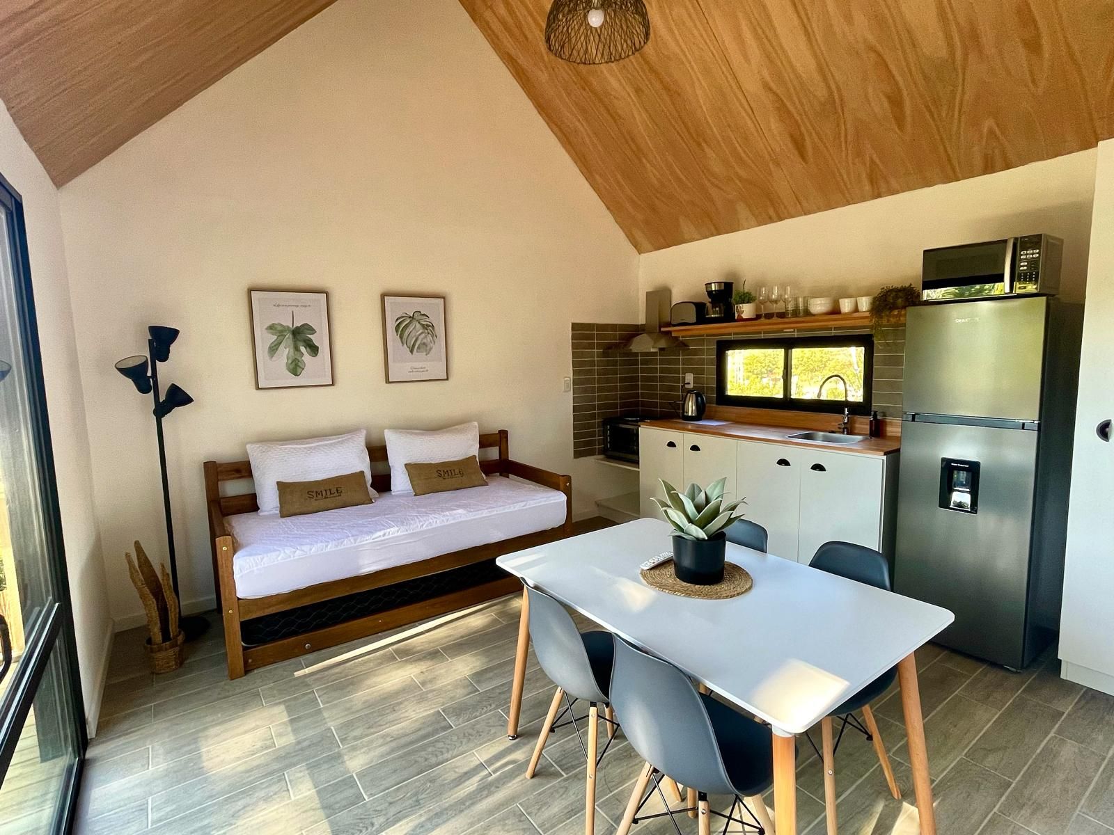 Un espacio habitable pequeño con cama, mesa de comedor y kitchenette.