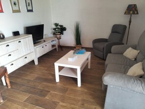 A living room with a sofa, a coffee table, a TV, a cabinet, and a plant. - Eagle Eyes 2 (Puente Avíos)