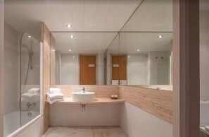 A modern bathroom with a glass shower enclosure, a sink with a mirror, and a wooden vanity. - Romantic Apartment Getaway by the Beach (Pals)