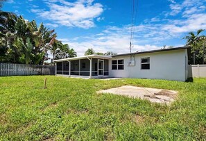 A single-story house with a covered porch, a fenced yard, and a clear sky. - Experience the best of Wilton Manors (Wilton Manors)