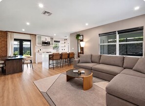 A modern living room with a sofa, coffee table, and a dining area with chairs. - Experience the best of Wilton Manors (Wilton Manors)
