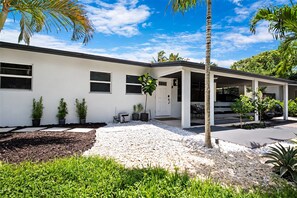 A modern two-story house with a covered porch, potted plants, and a gravel driveway. - Experience the best of Wilton Manors (Wilton Manors)