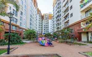 A residential area with multi-story buildings, a children's play area, and a paved walkway. - 3Br |stylish home | Game Park View Haven | Family friendly | Nairobi stay (Nairobi)