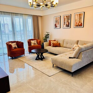 A modern living room with a sofa, two armchairs, a coffee table, and a chandelier. - 3Br |stylish home | Game Park View Haven | Family friendly | Nairobi stay (Nairobi)