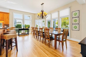 A spacious kitchen with a dining area, large windows, and a chandelier. - Casa del Sol Soundfront Currituck Club (Corolla)
