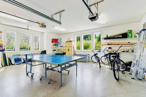 Una stanza con tavolo da ping pong, biciclette e un portabiciclette.