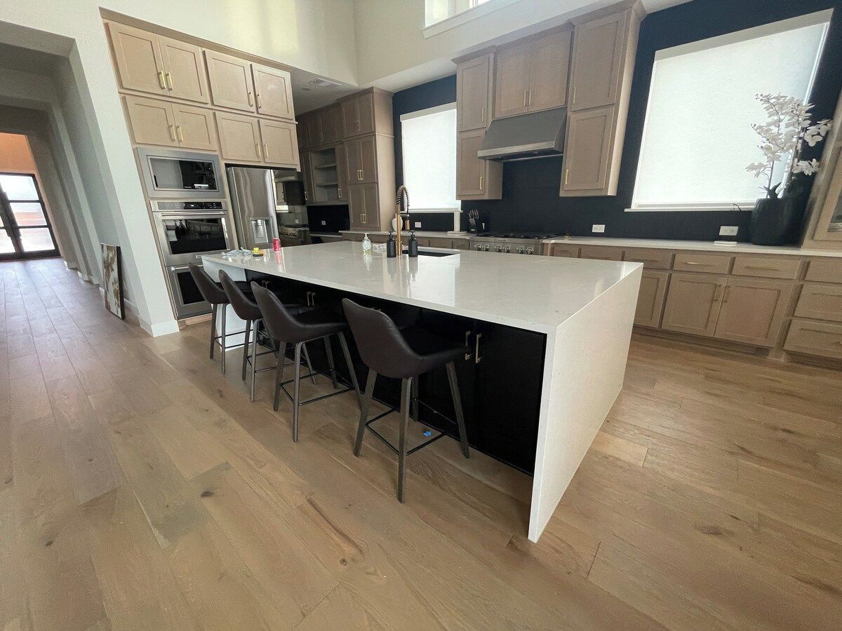 A modern kitchen with a central island, bar stools, and built-in appliances.