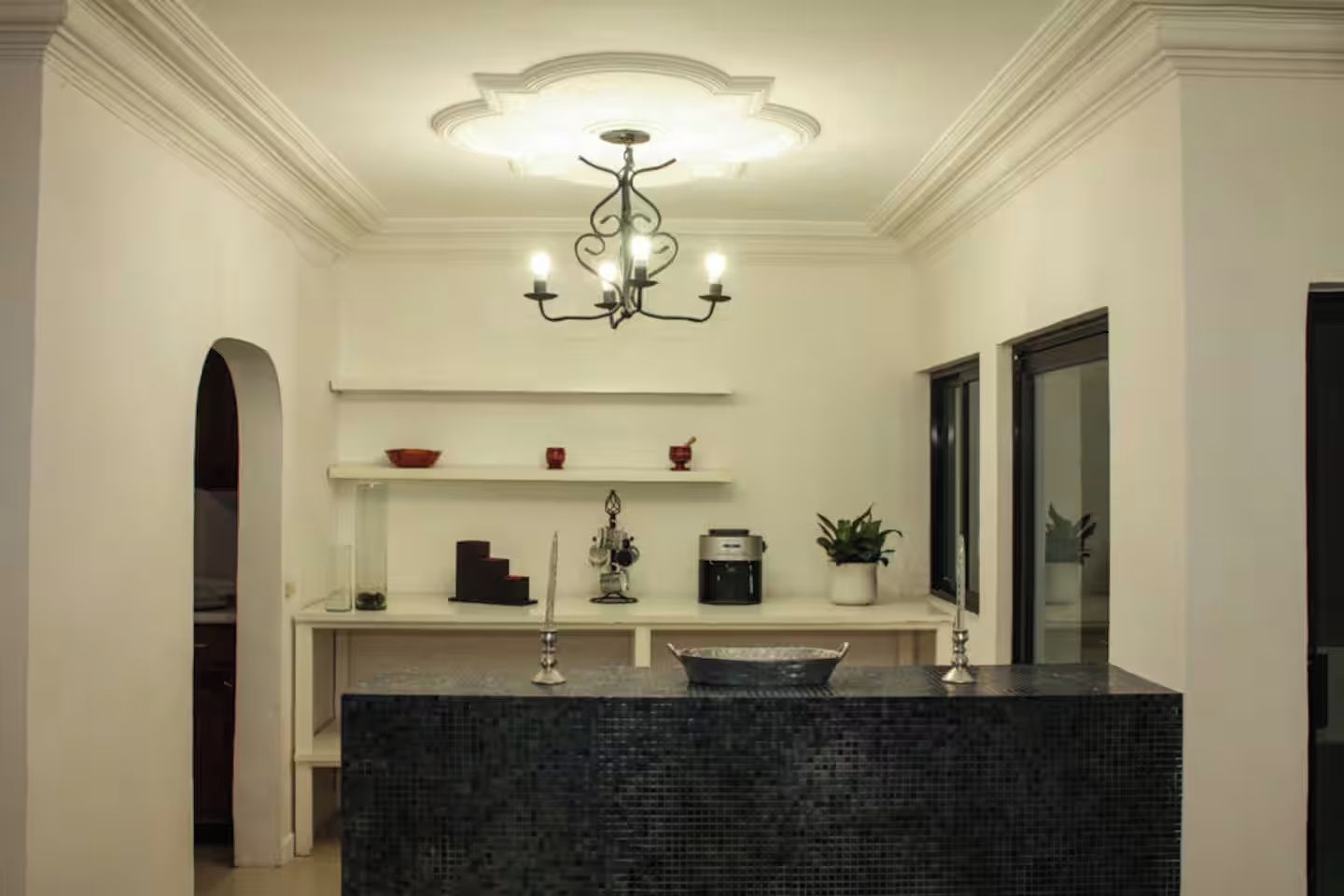 Une salle de bain moderne avec un lavabo en marbre foncé, un lustre décoratif et un miroir.