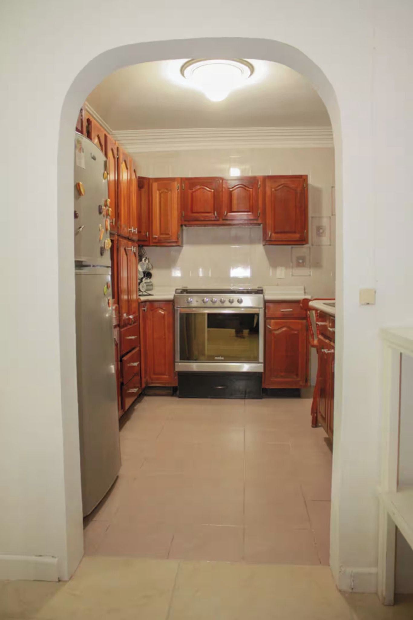 A kitchen with wooden cabinets, a stainless steel refrigerator, and a built-in oven.