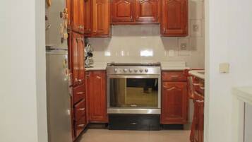 A kitchen with wooden cabinets, a stainless steel refrigerator, and a built-in oven.
