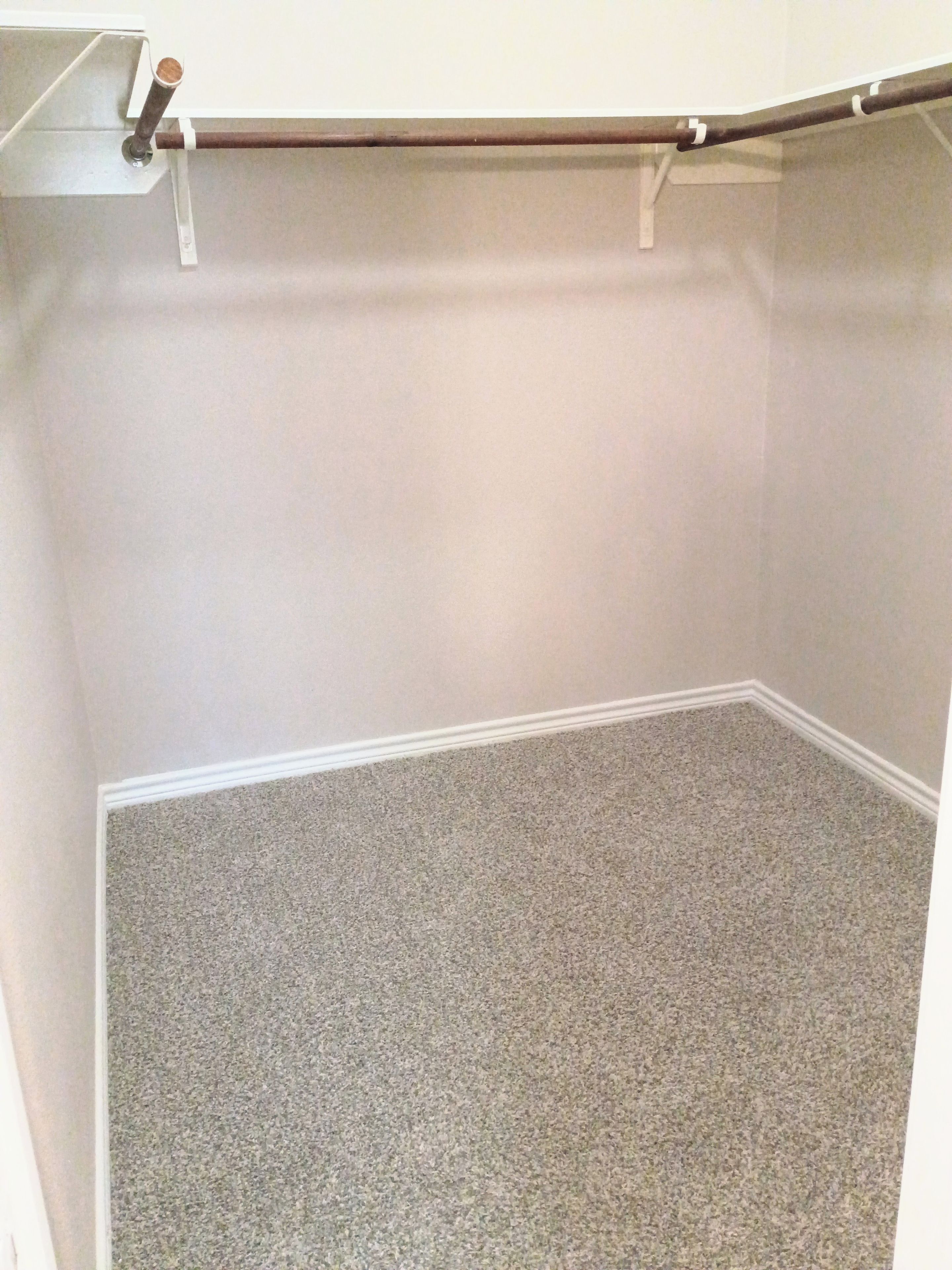 Een kamer met een vloerbedekking, een witte muur en een deur met een handgreep.