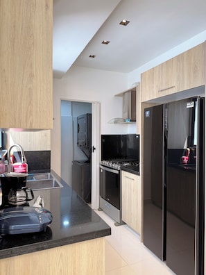 Una cocina moderna con estufa integrada, un refrigerador y una cafetera en la encimera.