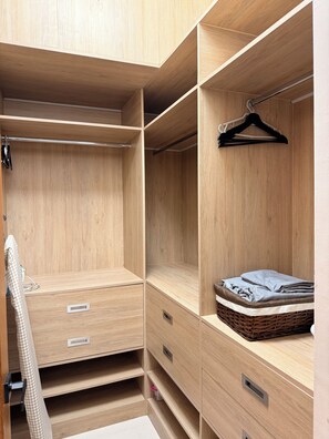 A wooden closet with multiple compartments, a hanging rod, and a wicker basket. - Stylish 1-Bedroom Apartment in the Heart of Santo Domingo (Santo Domingo)