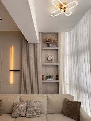 A modern living room with a sofa, decorative pillows, a wall-mounted clock, and a ceiling light fixture. - Stylish 1-Bedroom Apartment in the Heart of Santo Domingo (Santo Domingo)