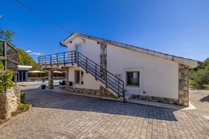 A two-story house with a stone facade, a pool, and a staircase. - Apartment ADVIMA with private heated pool (Žestilac)