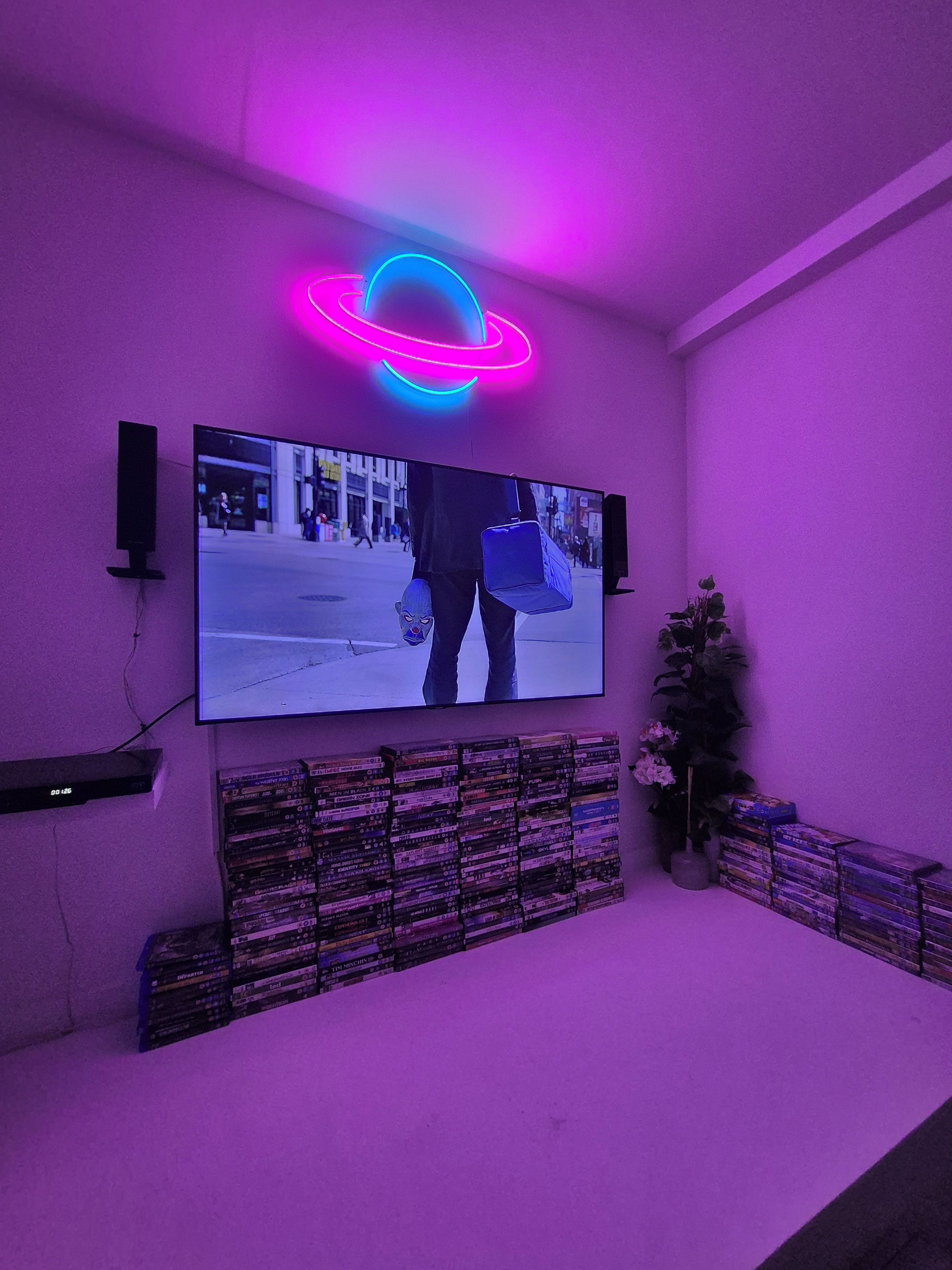 Una stanza con una televisione fissata al muro, circondata da una collezione di DVD.