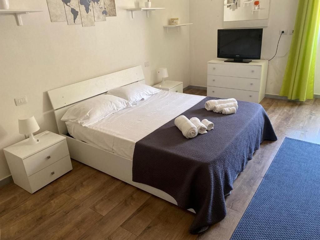 A hotel room with a bed, a TV, a bedside table, and a lamp.