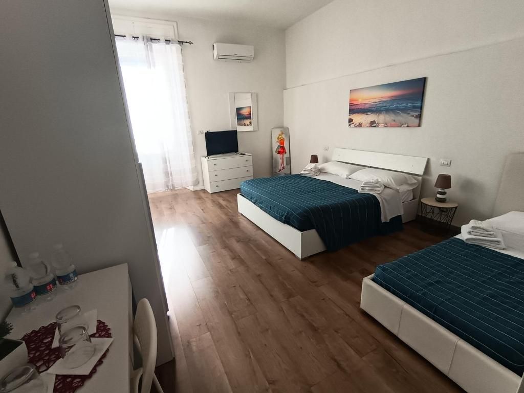 Un dormitorio con dos camas, un escritorio, una silla y una ventana con cortinas.