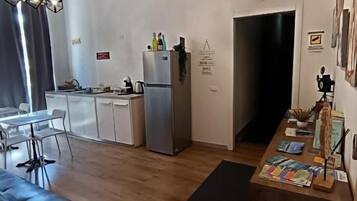 A modern kitchen with a dining area, a black sofa, and a wooden table with books.