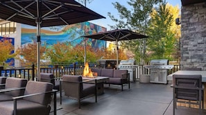 Un patio exterior con mobiliario, una chimenea y una parrilla.
