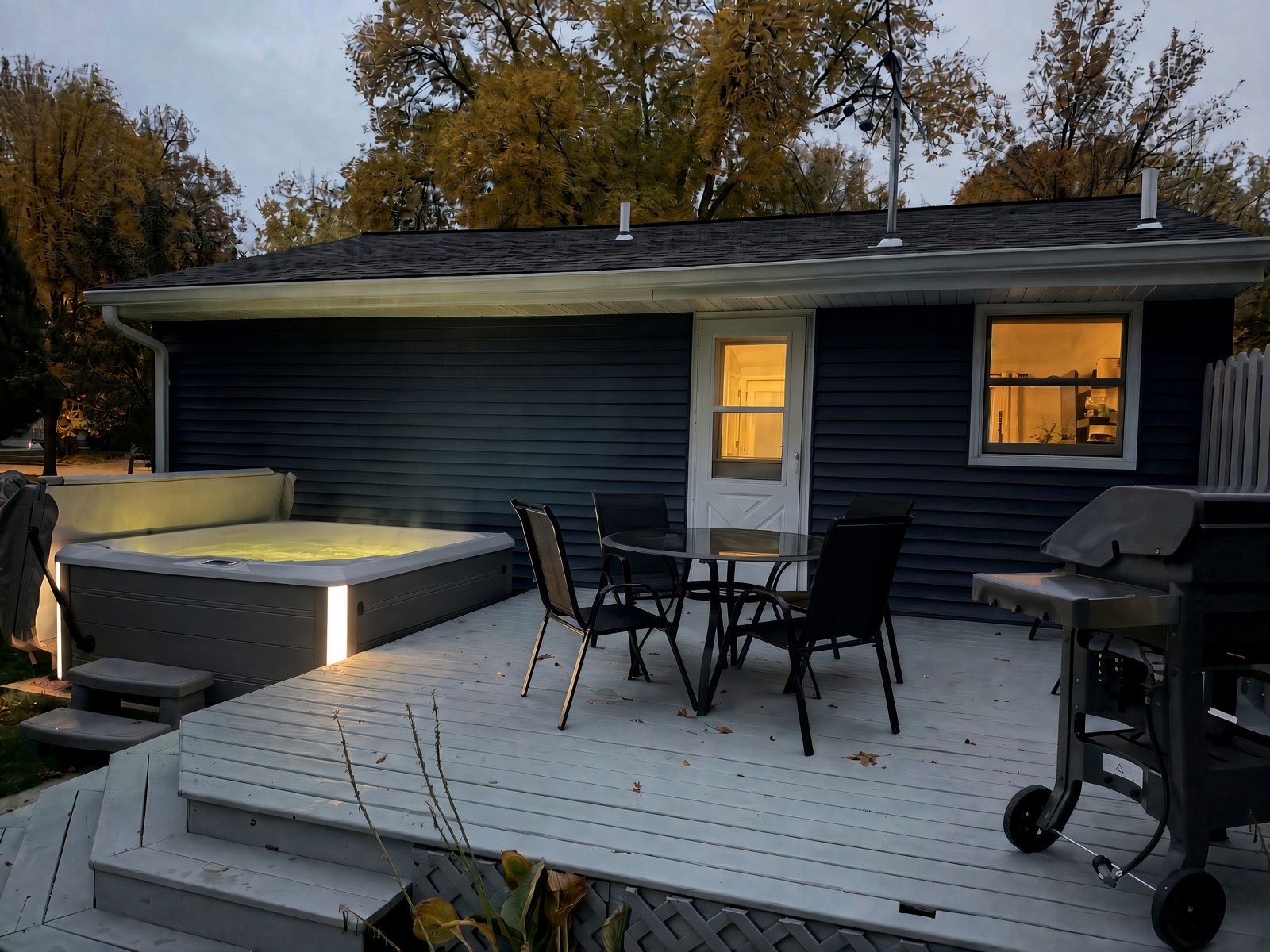 En terrasse med jacuzzi, udendørs møbler og grillplads.