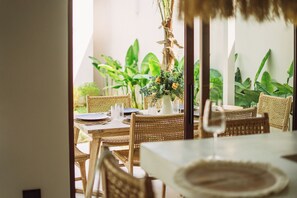 An outdoor dining area with wicker furniture, a table set with plates and glasses, and a vase with flowers. - Villa Pearl — Easy Island Living, Your Way (Ko Samui District)