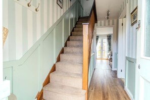 A staircase with carpeted steps leading to a landing, flanked by light-colored walls with vertical stripes and a wooden handrail. - Dutch Cottage Cotswold Stay with Private Parking (Gloucestershire)