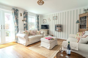 A living room with two sofas, a coffee table, a TV, and a cabinet. - Dutch Cottage Cotswold Stay with Private Parking (Gloucestershire)