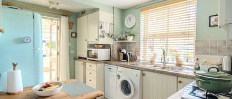A kitchen with a washing machine, a stove, and a sink.