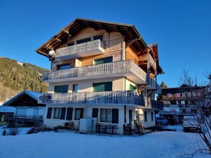 A multi-story wooden building with balconies, a ski lift, and a snowy landscape. - 300m from ski slopes, 2nd floor, balcony, tv, ski locker, 47m², Les Gets (Les Gets)