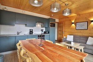 A modern kitchen with grey cabinets, a wooden dining table, and pendant lighting. - 300m from ski slopes, 2nd floor, balcony, tv, ski locker, 47m², Les Gets (Les Gets)