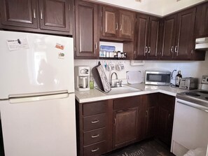 A kitchen with a refrigerator, coffee maker, microwave, toaster, and wooden cabinets. - Charming condo in gorgeous Marco Island perfect for your getaway (Marco Island)