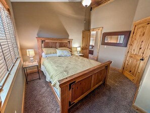 A bedroom with a wooden bed, two bedside tables with lamps, a mirror, and a wardrobe. - McCall Mountain Escape | Loft, Deck & Ping Pong (McCall)