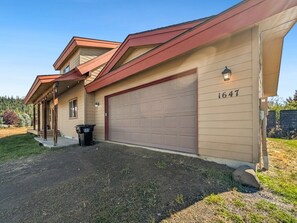 A two-story residential building with a garage, a covered porch, and a well-maintained lawn. - McCall Mountain Escape | Loft, Deck & Ping Pong (McCall)