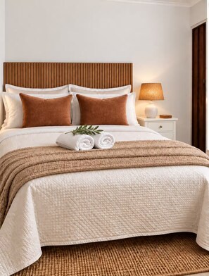 A neatly made bed with a headboard, pillows, and a rolled towel. - Zen Nest • Cozy Studio • 3-Min Drive to Palm Beach (Noord)