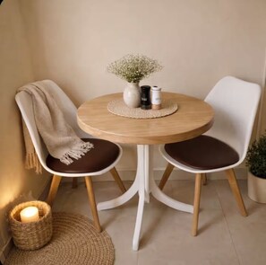 A round wooden table with two chairs, a vase with flowers, and two salt and pepper shakers. - Zen Nest • Cozy Studio • 3-Min Drive to Palm Beach (Noord)