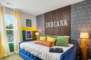 A hotel room with a large bed, a view of the outdoors, and a wall with the word 'INDIANA' on it. - Indy Escape | Sauna, Hot Tub, Firepit & Games (South Bend)