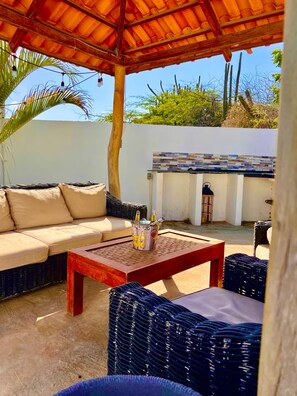An outdoor seating area with a wooden table, wicker furniture, and a sofa. - Romantic King Studio w/ Private Jacuzzi Palm beach (Noord)